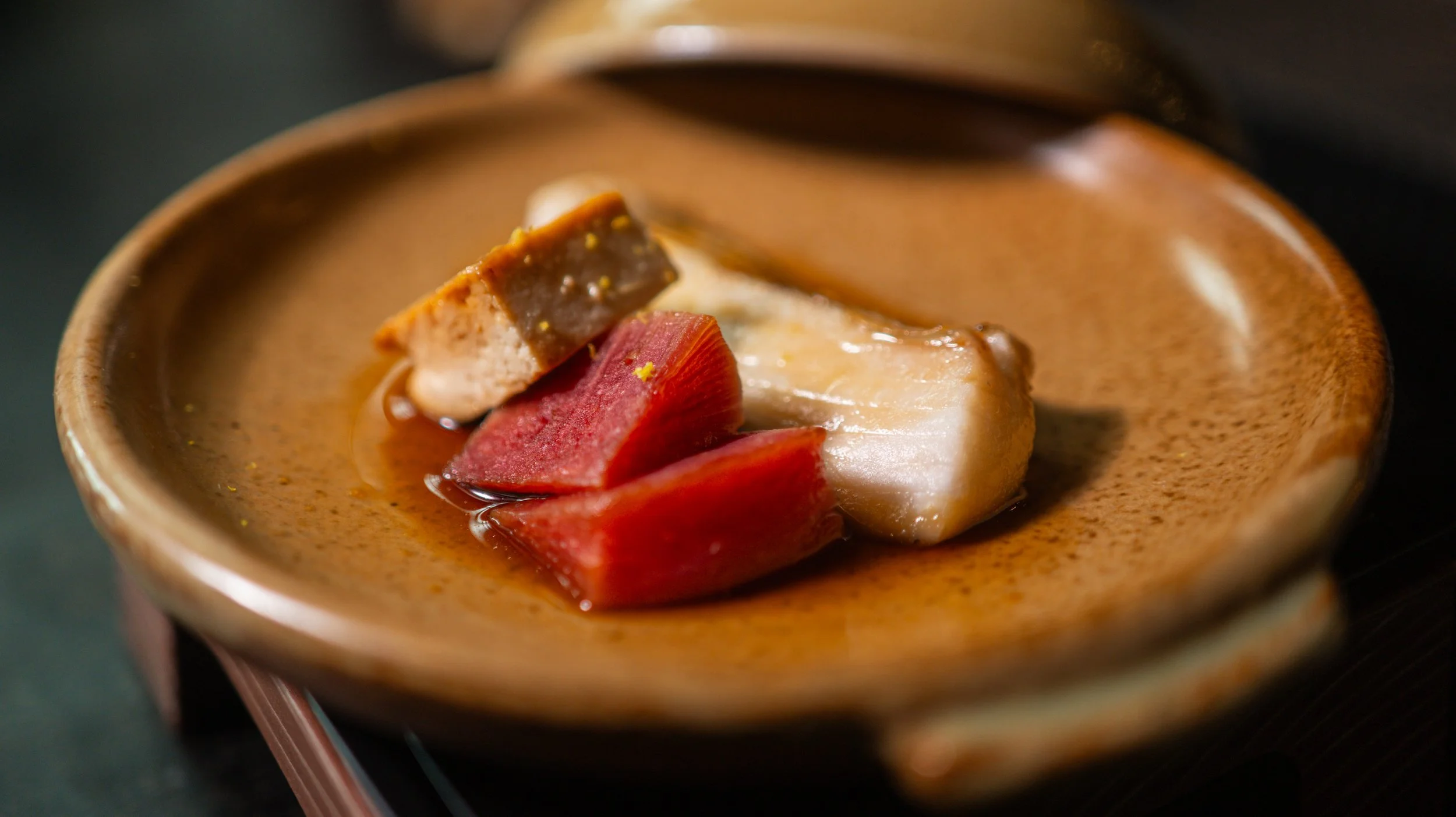 A decadent Kaiseki course at Yugen Sarasota featuring premium bluefin tuna and seared foie gras in a rustic ceramic bowl.
