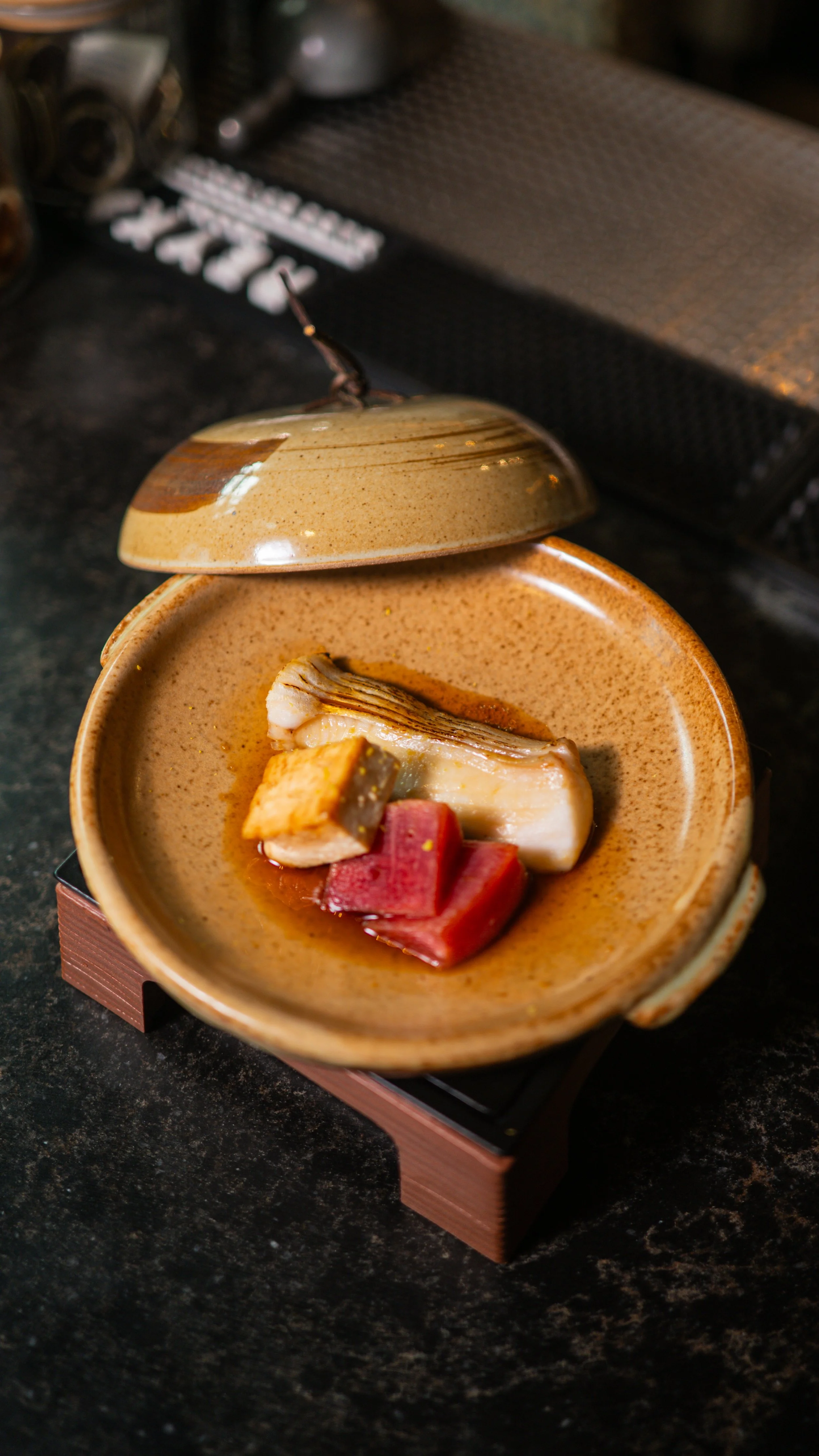 A traditional Japanese "Wanmono" or lidded soup course being served at the Yugen chef's counter.