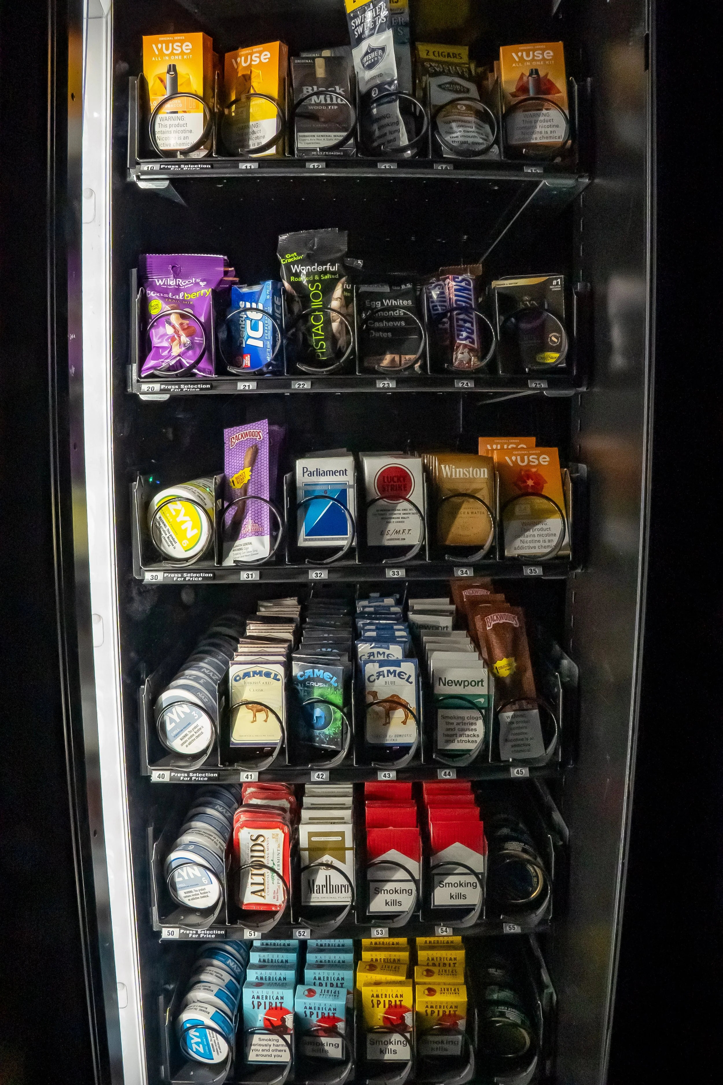 Vending machine with various cigarette brands and packs on multiple shelves.