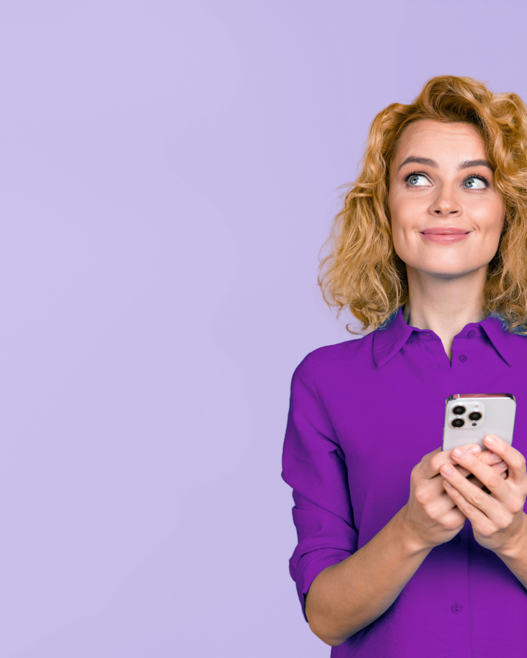 A woman with curly blonde hair wearing a purple shirt, holding a smartphone and smiling while looking to the side, against a light purple background.