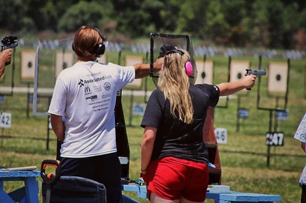 Victoria LaBrosse standing with her arm outstretched at a pistol competition