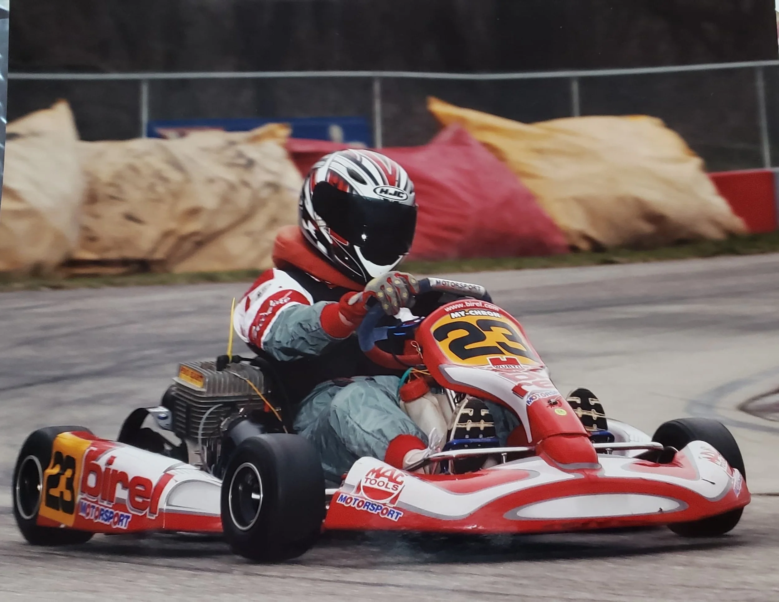 Victoria LaBrosse wearing a helmet and a racing suit racing a go cart on a track