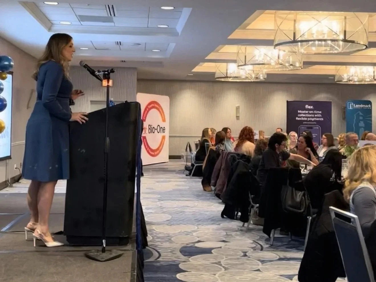 Victoria LaBrosse speaking at a podium in front of a crowd at a community event