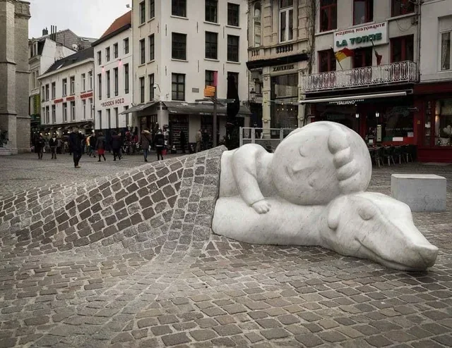  In Antwerp, Belgium, you can find this sculpture…It depicts Nello and Patrasche, the heroes of the 19th-century novel A Dog of Flanders, sleeping under a cobblestone blanket.