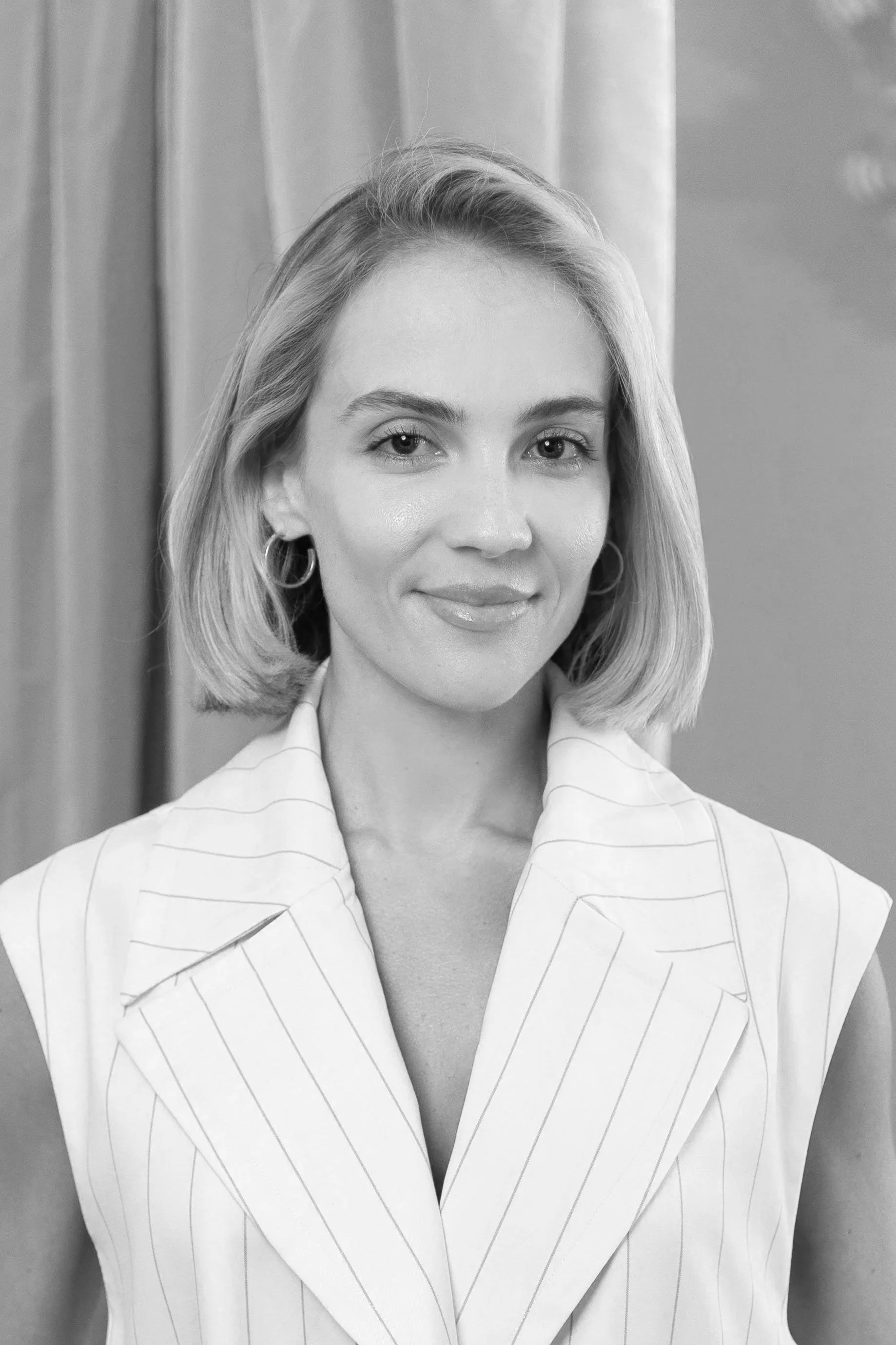 A woman with short blonde hair wearing a pinstripe blazer.