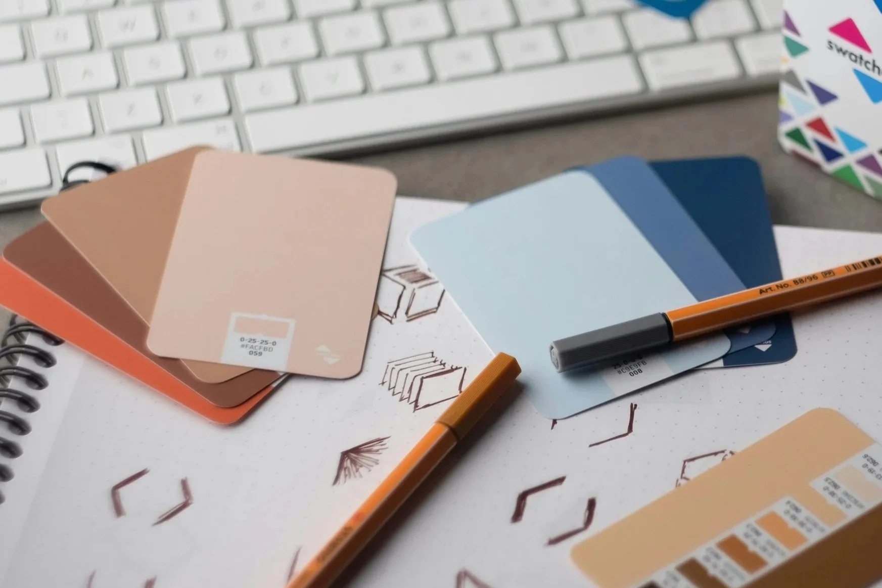 Color swatches and sample ideas on a desk with a keyboard in the background.