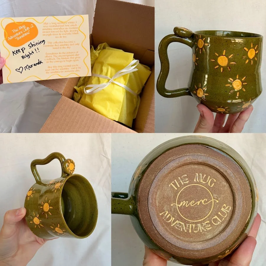 A cardboard box containing a yellow-wrapped item with a handwritten note and a yellow ribbon. Next to it, a handmade ceramic mug decorated with yellow sun and flower designs. The mug has a curved handle and a circular logo on the bottom reading 'THE Mug MERC ADVENTURE CLUB.'