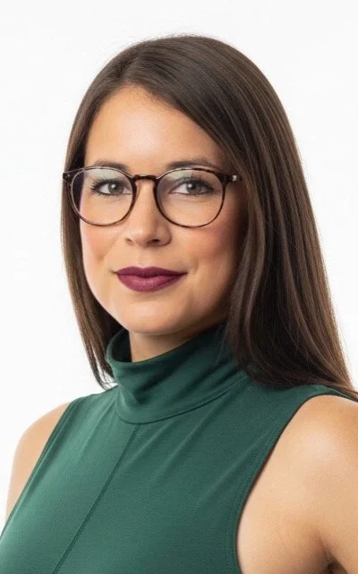 A woman with long brown hair, wearing glasses and a white top, looking at the camera.