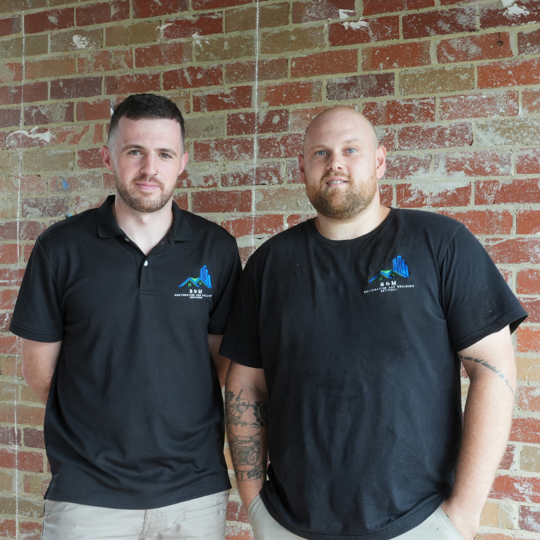 ben and matt from bm restorations smiling together in front of a brick wall