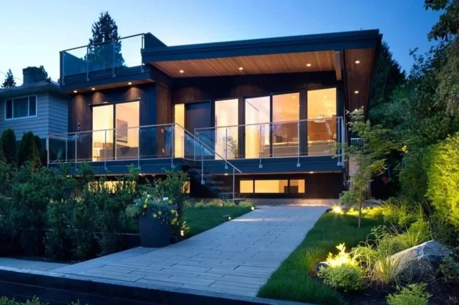 Contemporary North Shore home at dusk with illuminated glass railings and landscape lighting along the entry path