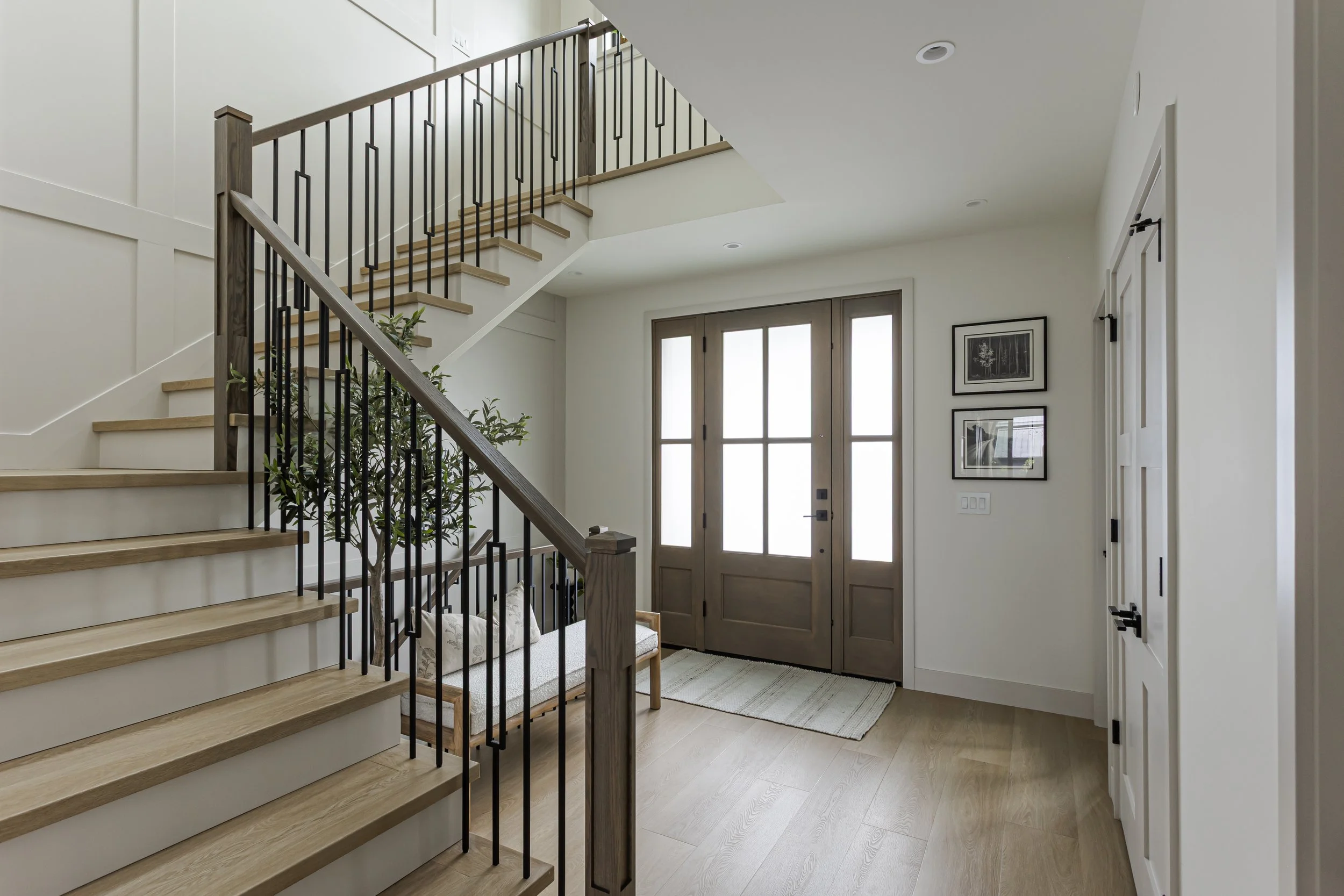 Front entryway with a curved wood-and-iron staircase, glass-panel front door, and built-in bench seating