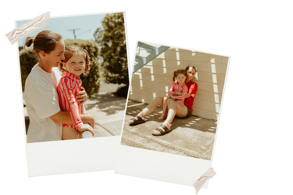 A woman and a young girl, both wearing red and white striped shirts, sitting together outdoors in sunny weather, with trees and a fence in the background.