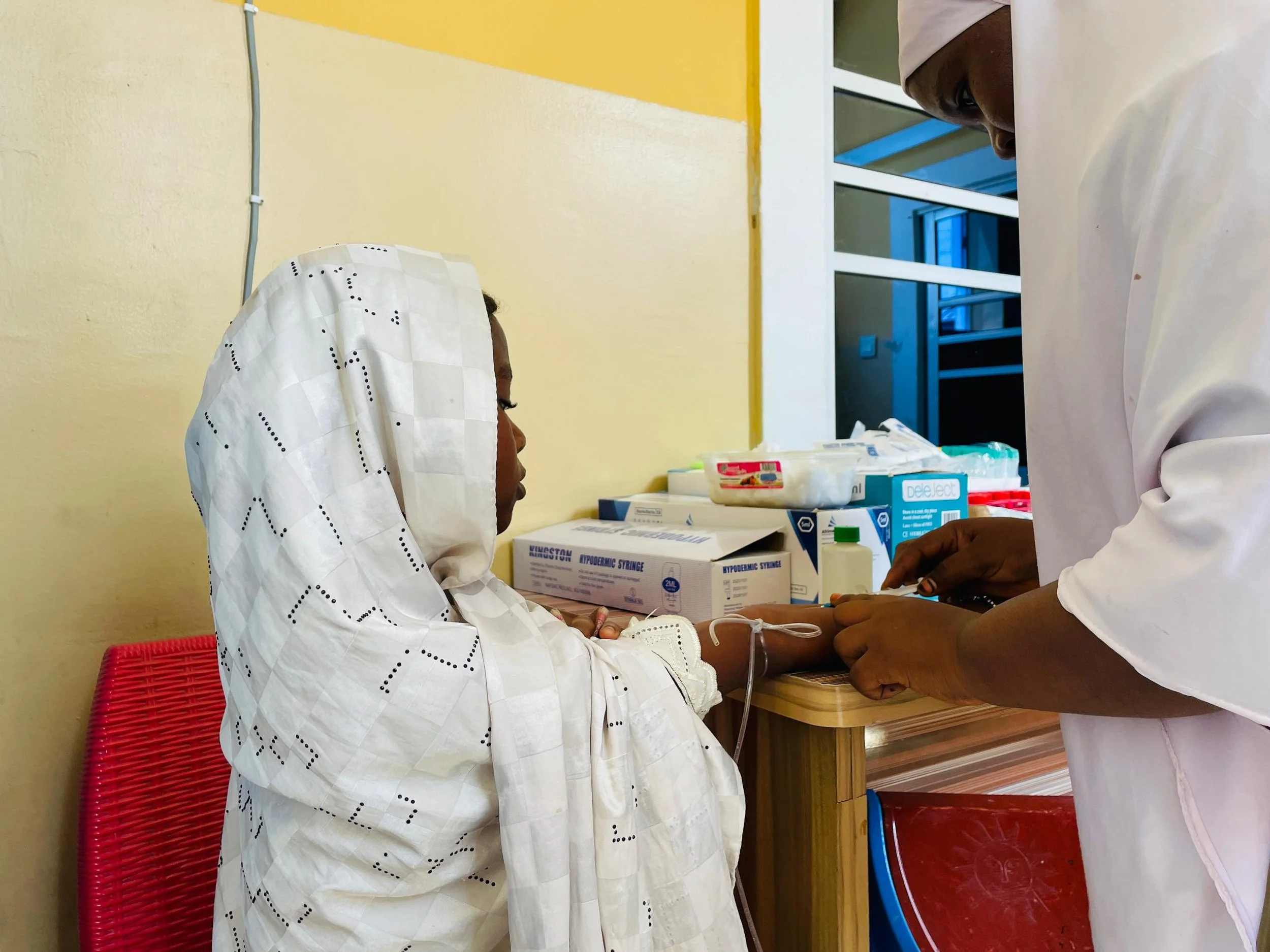A healthcare worker preparing to give a patient an injection in a medical clinic.