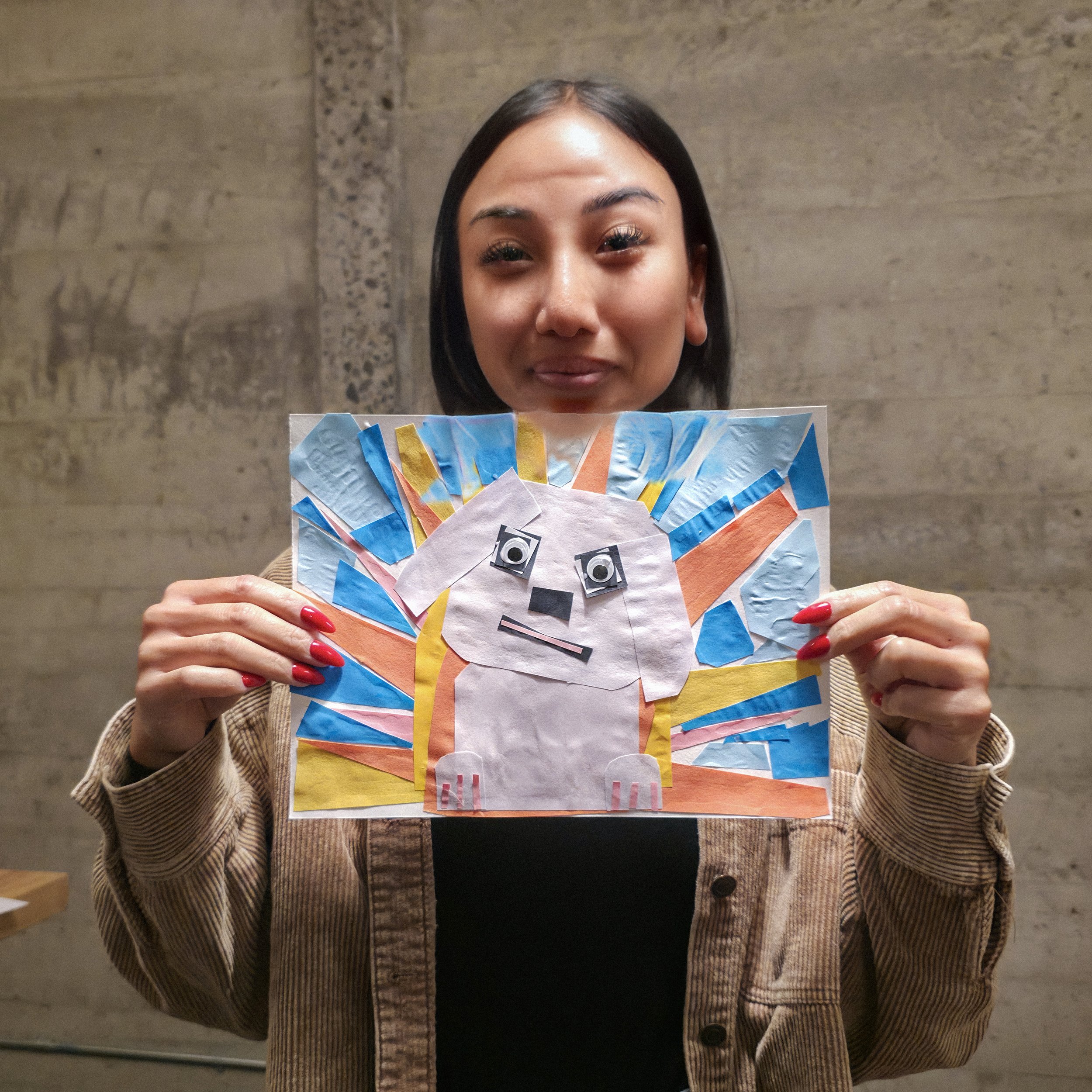 Woman holding a colorful handmade paper collage featuring a stylized face