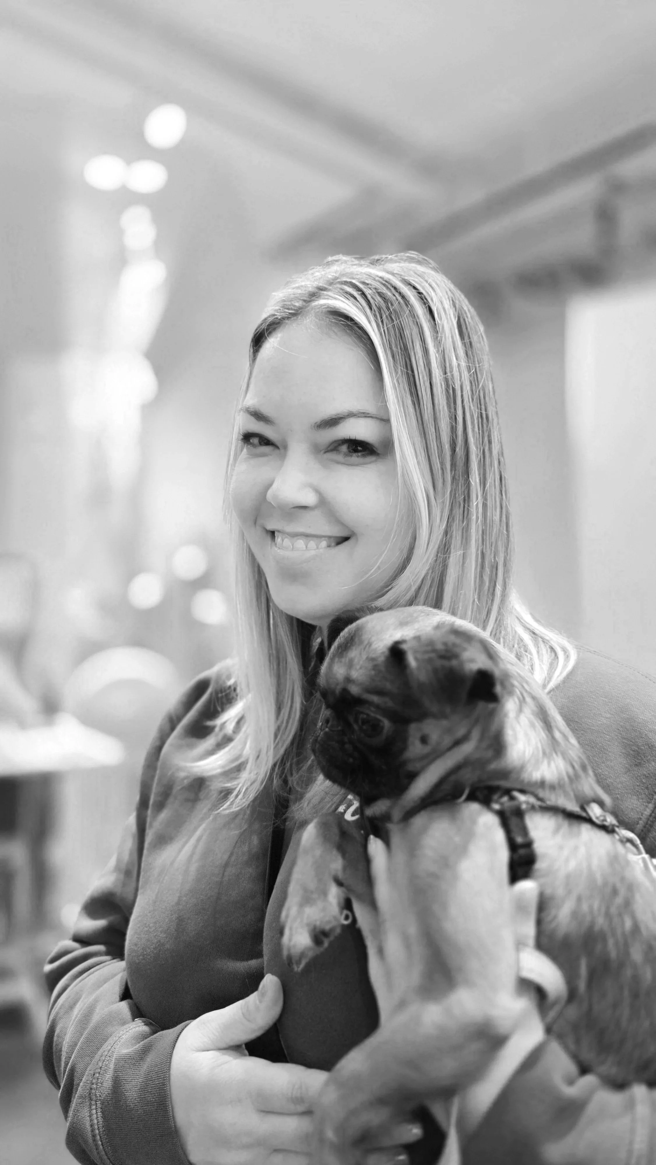 Smiling woman holding a small dog indoors