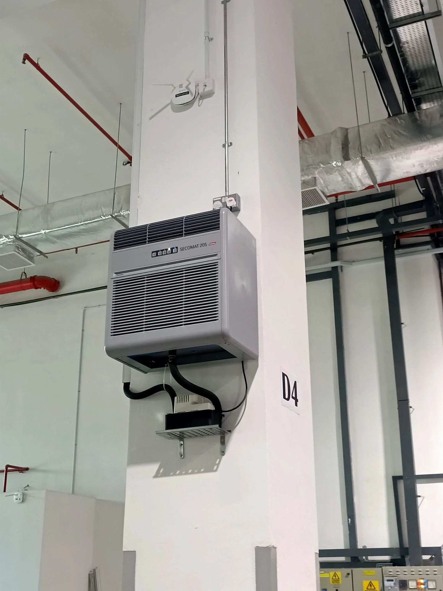 Dehumidifier unit mounted on a white wall in an industrial or commercial building.