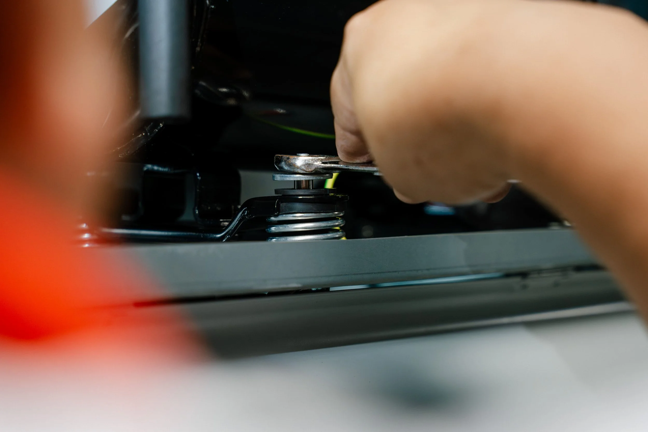 A person's hand turning a screw on a mechanical device with a spring, part of a dehumidifier unit.