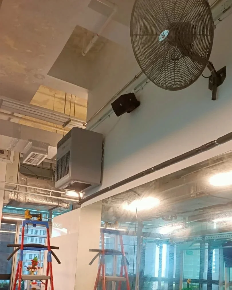 Ceiling fan, HVAC vent, speakers, and drywall in an indoor construction or renovation site with ladders and glass windows.