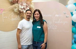 Two people standing in front of a pink and blue-themed backdrop at a fundraising event in 2022.
