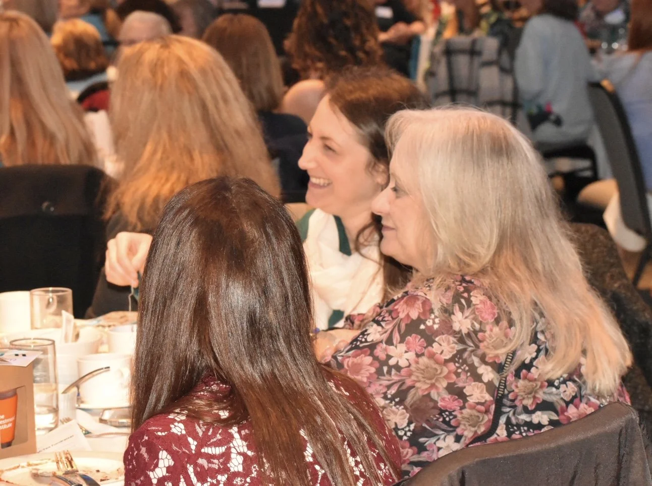Women sitting at a banquet table, engaged in conversation at a social event.