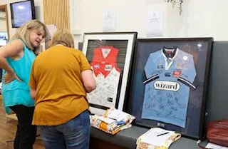 Children looking at framed Harry Potter-themed jerseys and memorabilia on a table.