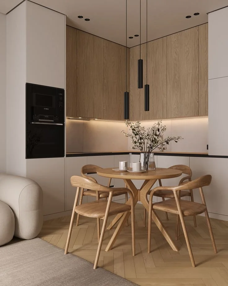 Modern kitchen with wood and white cabinetry, black accents, and a wooden dining table with four matching chairs, a vase with flowers, and three candles.