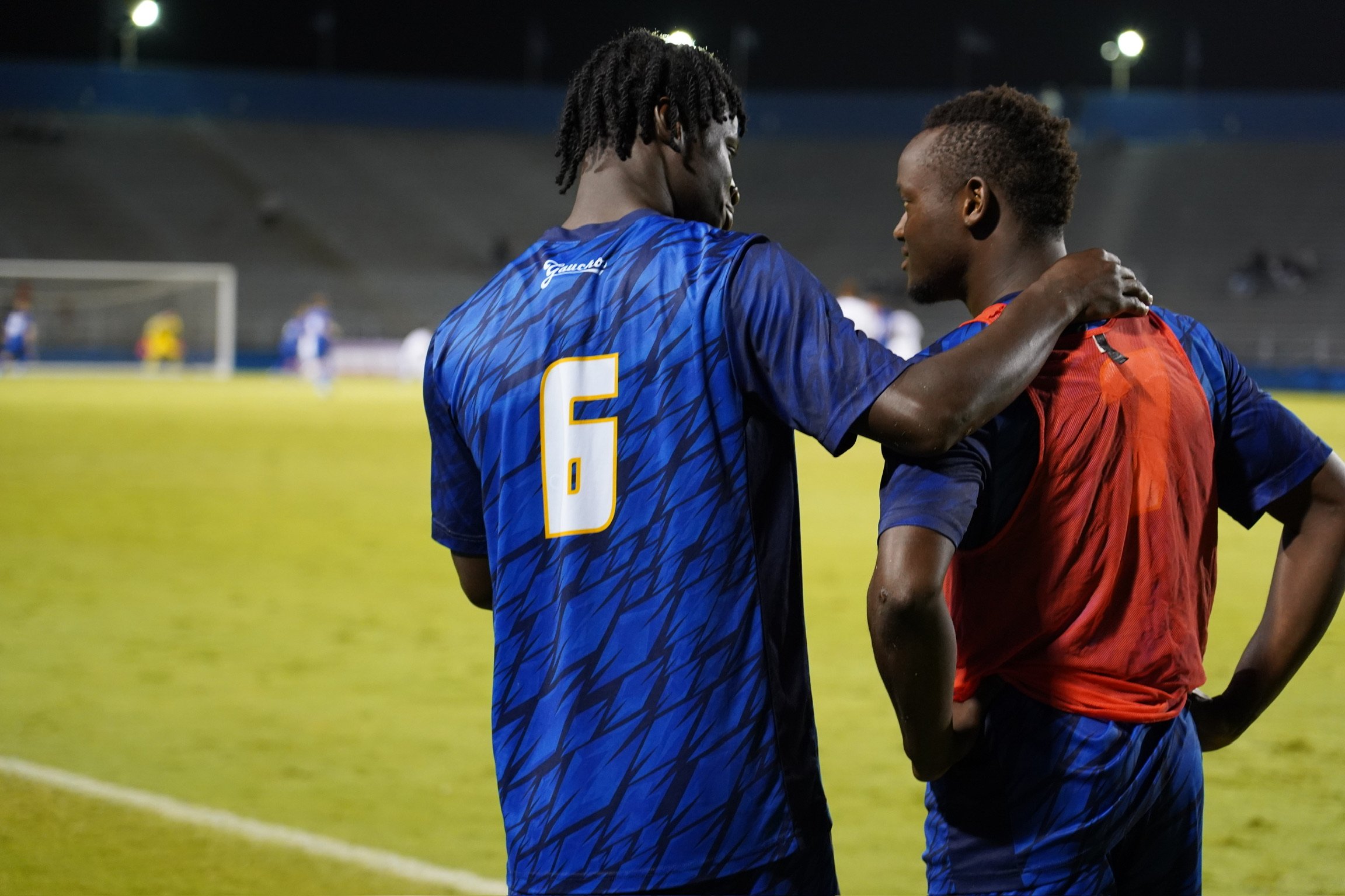 Justin Gomes giving Buba Fofanah words of encouragement as he heads into the game, a candid moment of friendship and connection caught just before he enters the game. 