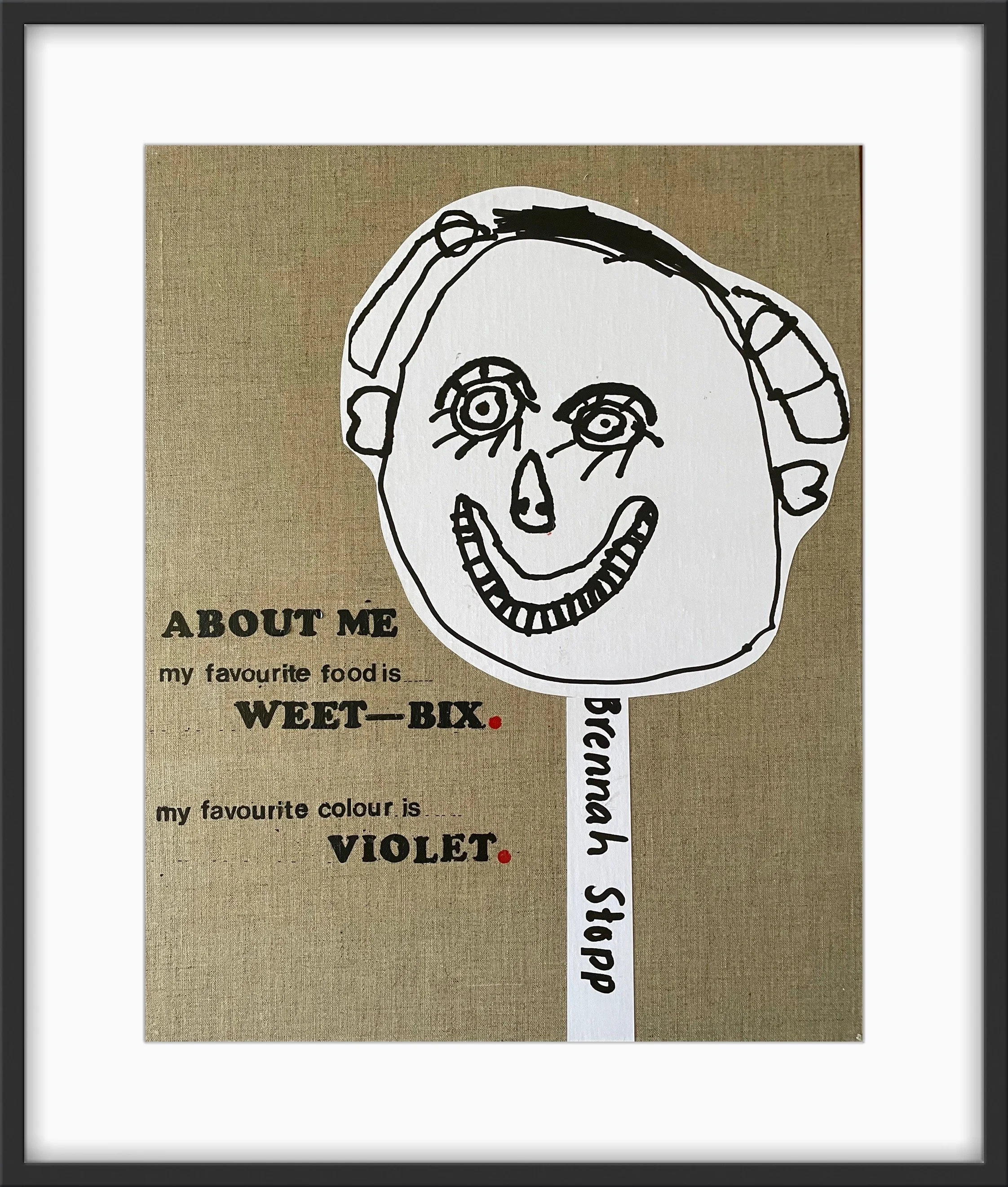 Child's drawing of a smiling face with the name Branah Slopp written vertically on a white strip. The background features printed text about a favorite food and color, with the words 'about me,' 'my favorite food is WHEET-BIX,' and 'my favorite colour is VIOLET.'