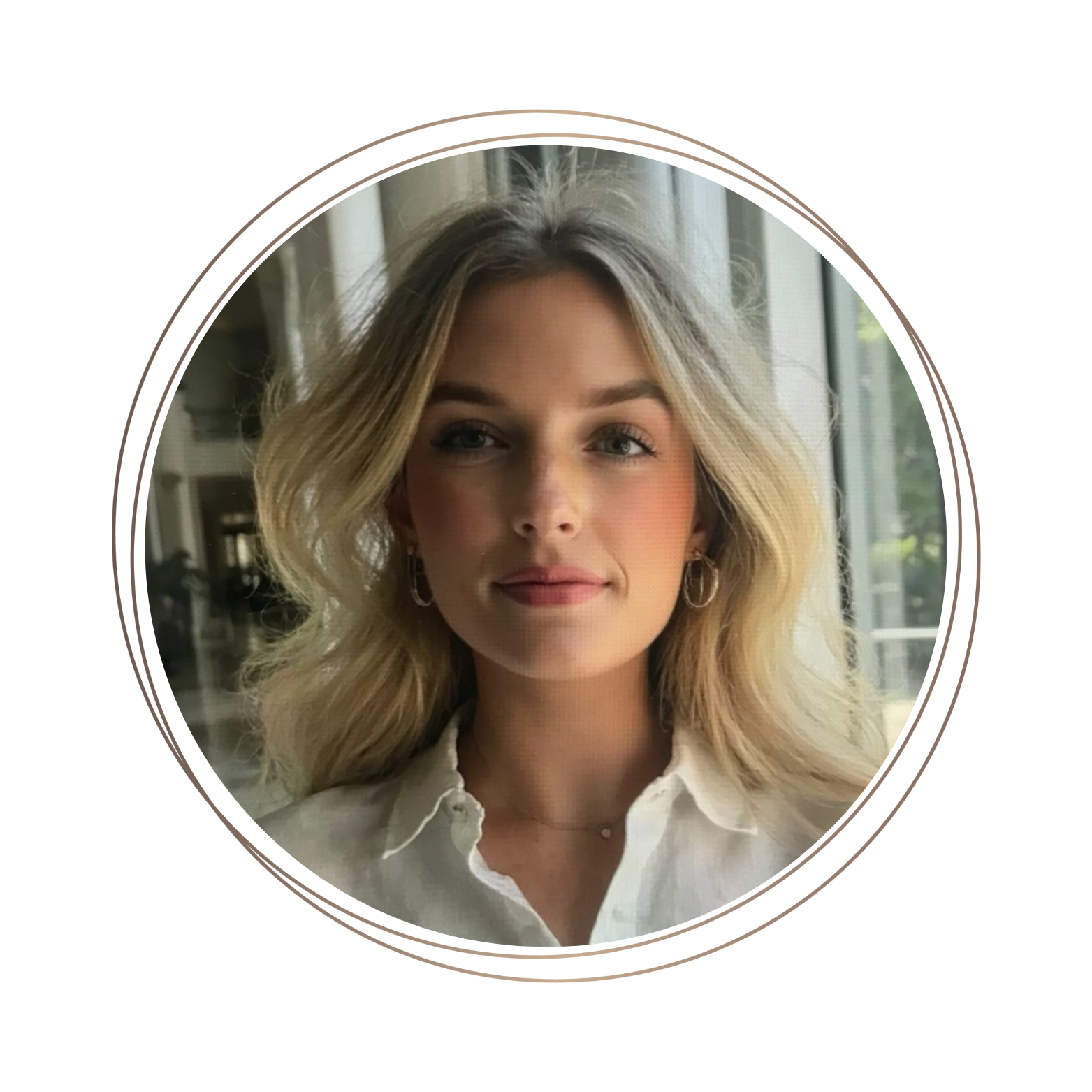 A woman with blonde, wavy hair and blue eyes, wearing a white collared shirt and hoop earrings, sitting indoors next to a window with natural light.