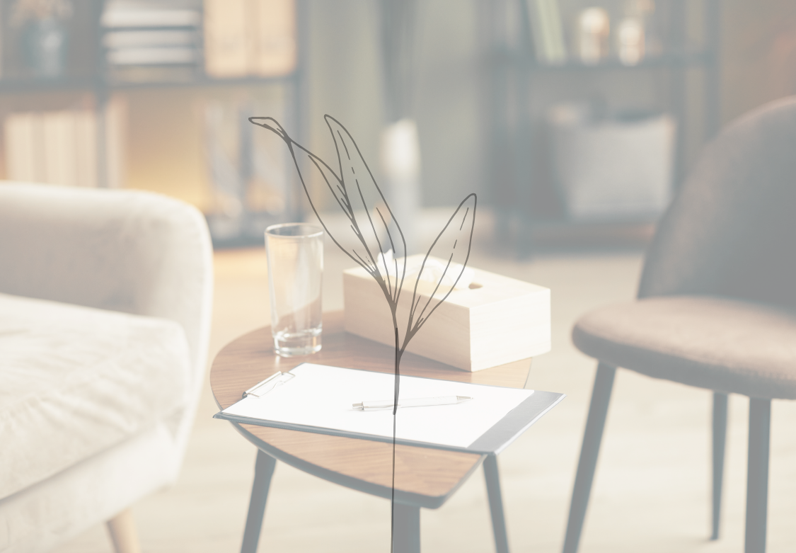 A cozy living room with a small round wooden table, a glass of water, a closed book, a pen, and a tissue box. In the foreground, there are two chairs and in the background, a bookshelf.