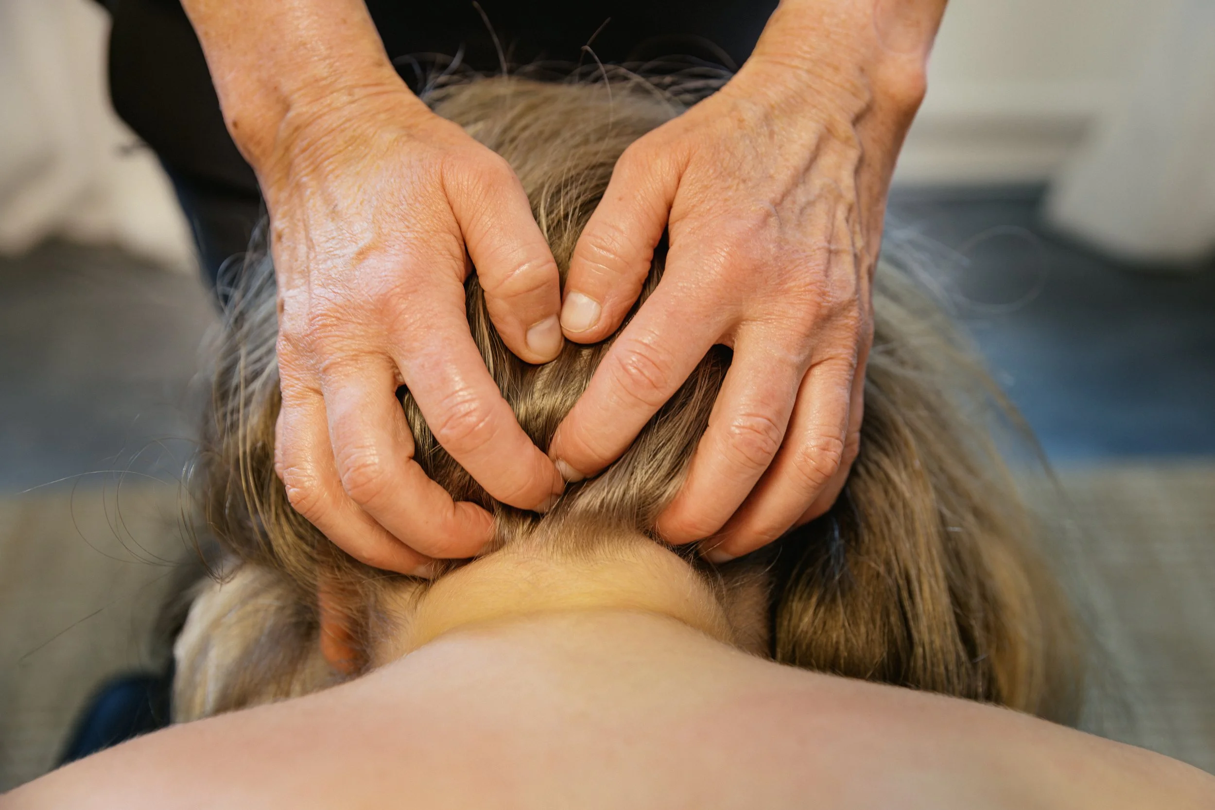 Person som ger en nackmassage till en annan person med långt blont hår.