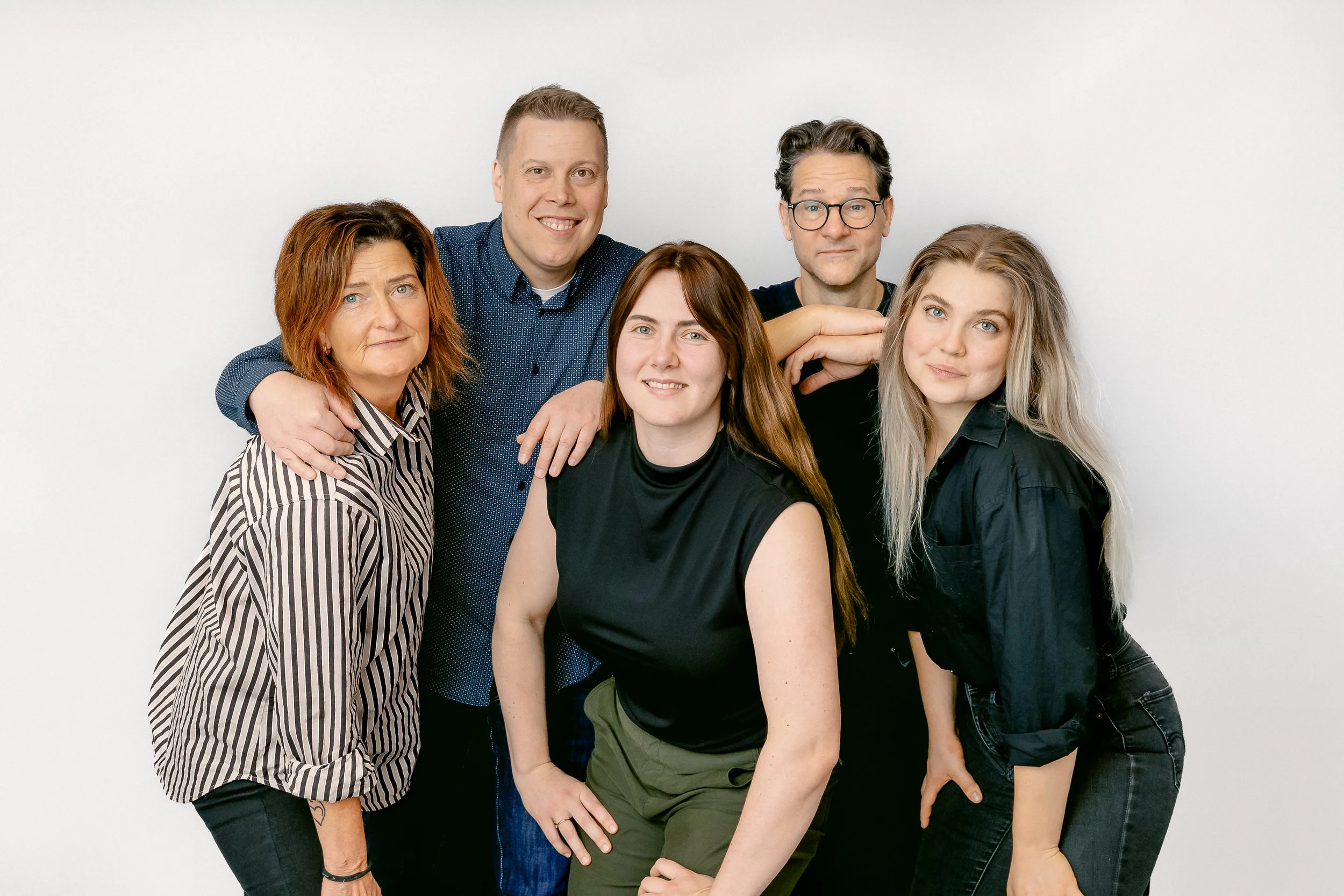 Grupp av fem personer som poserar inför en vit bakgrund, tre kvinnor och två män.
