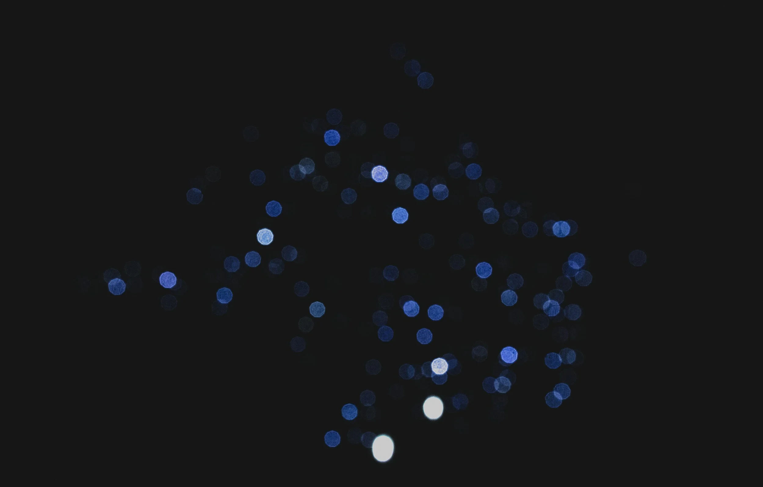 Blaue Weihnachtslichter gegen einen schwarzen Hintergrund, unscharf mit Bokeh-Effekt