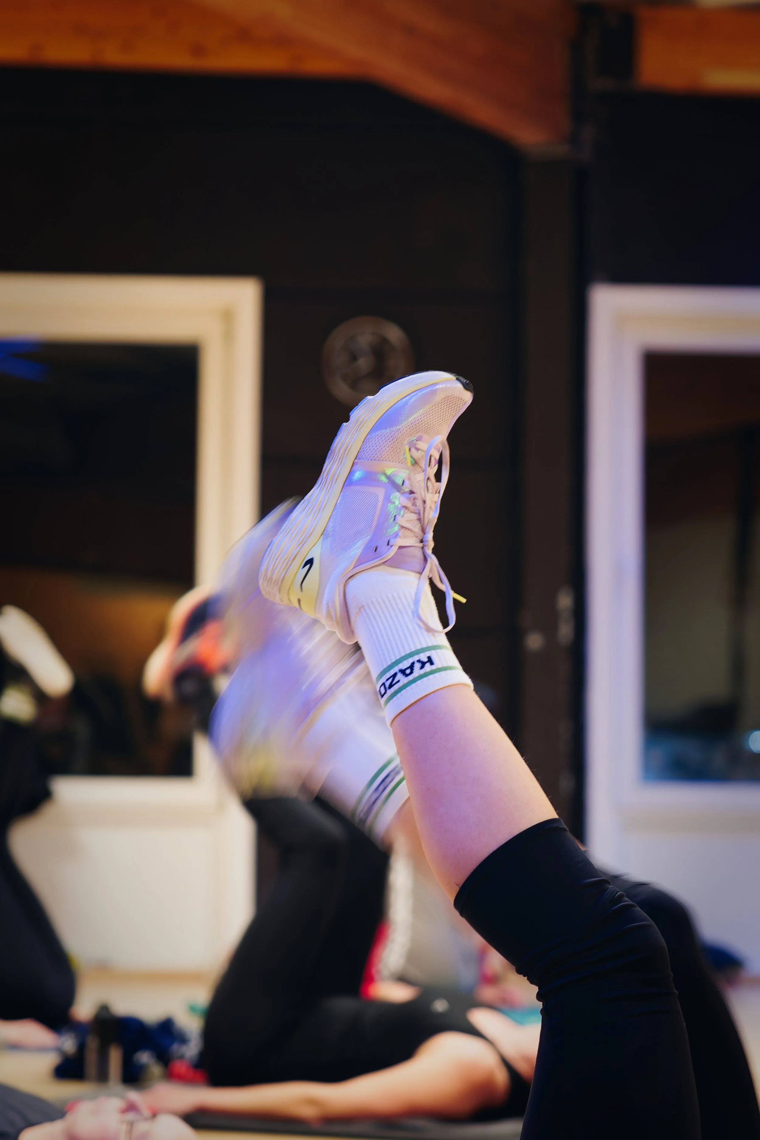 Persoon die in een yogahouding ligt met gestrekte benen omhoog in een fitnessruimte.