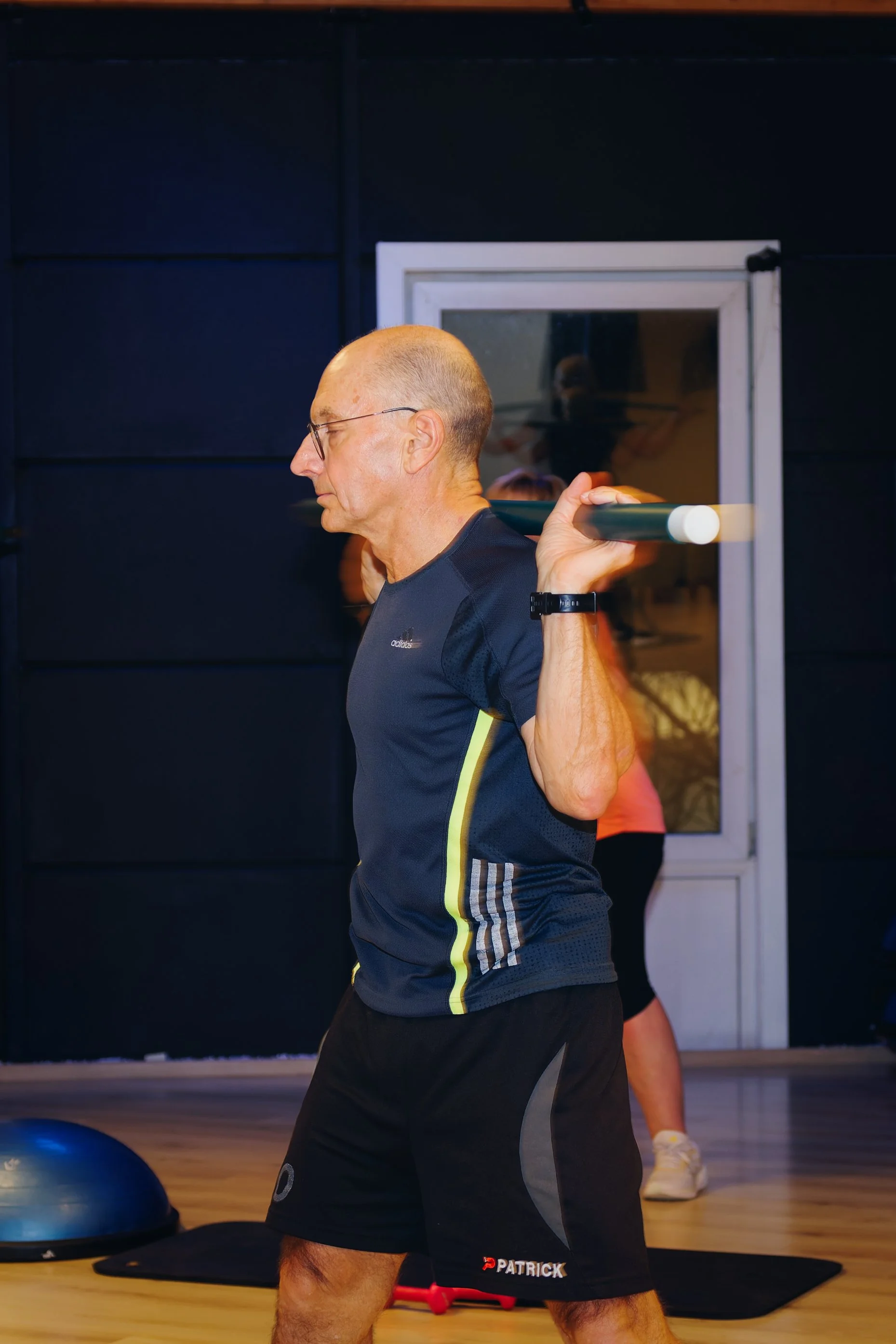 Man die een halter over zijn schouder tilt tijdens krachttraining in een sportschool.