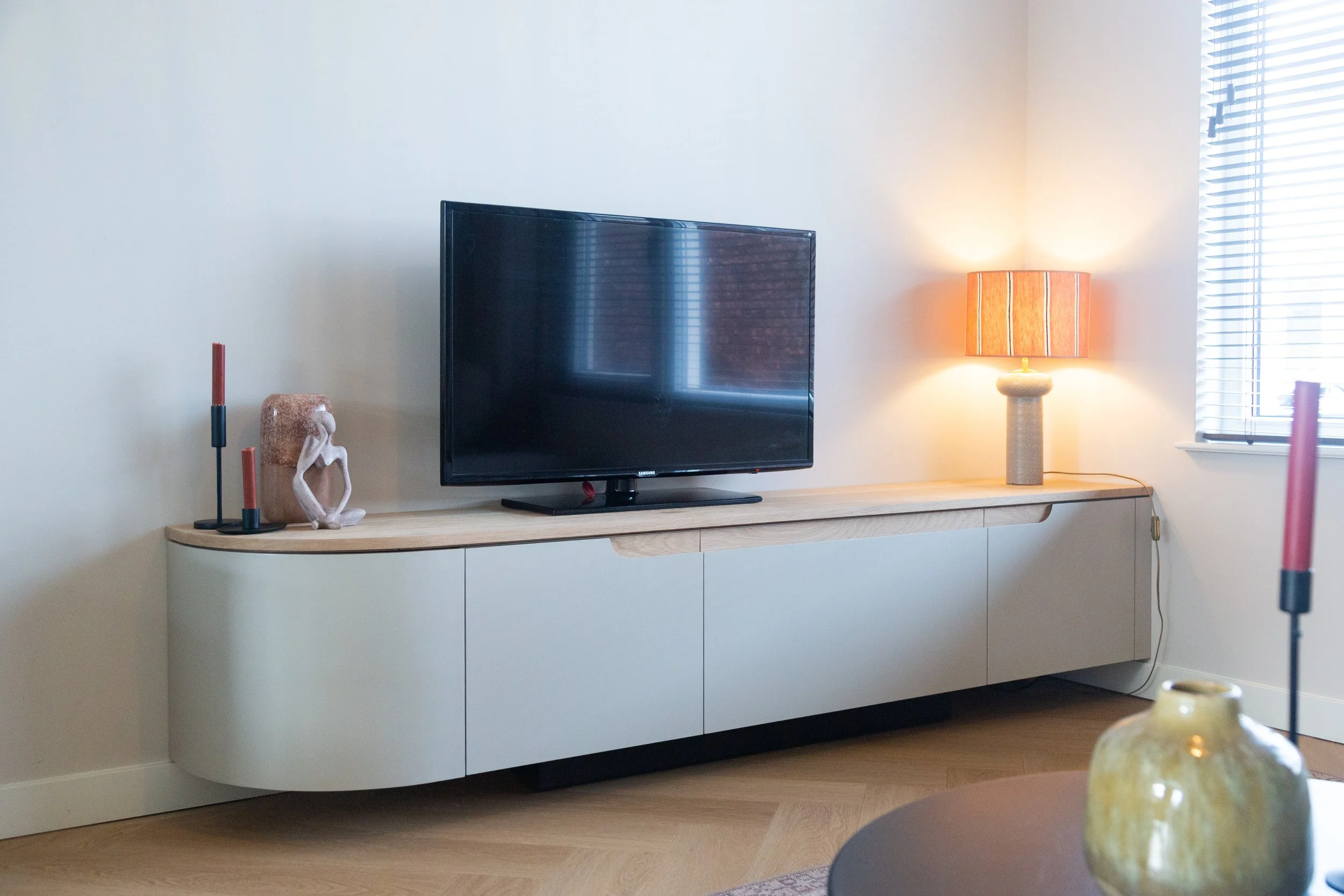 Tv-meubel in gelakt mdf met eiken blad. Eén kant half rond.