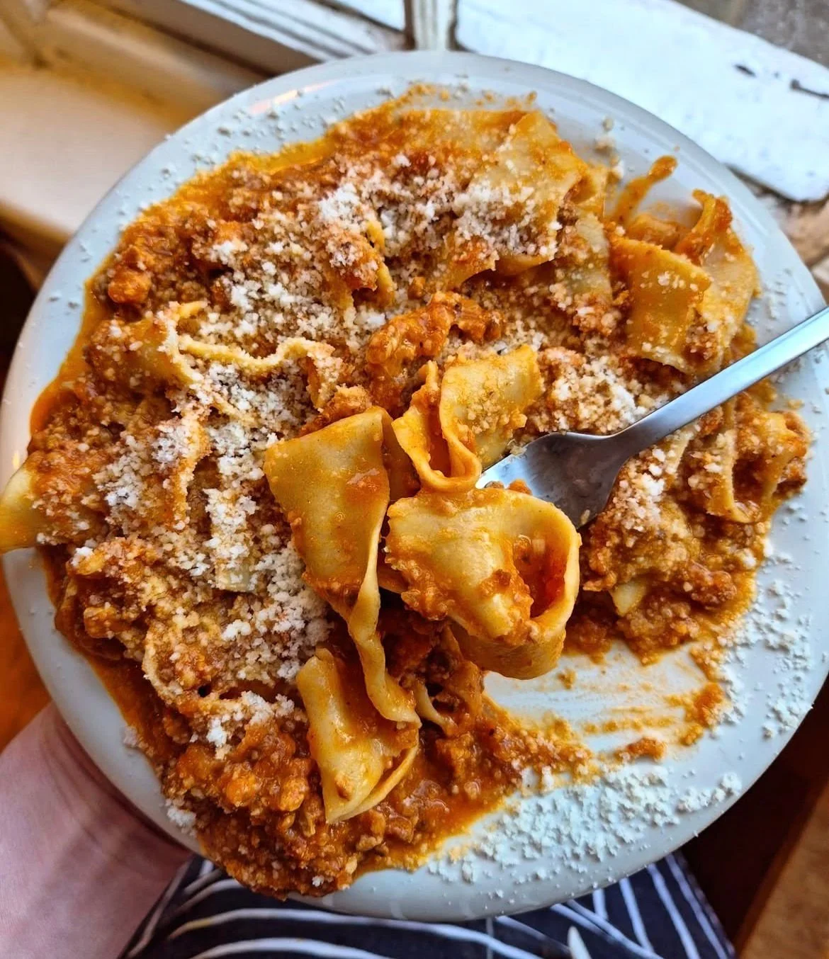 A plate of tortellini pasta with tomato sauce and grated cheese on top.