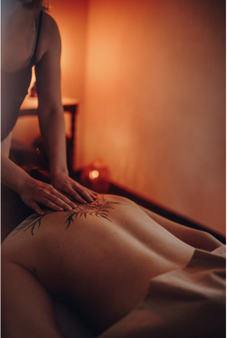 Inimene masseerib hämaras ja sooja valgusega ruumis kellegi selga.