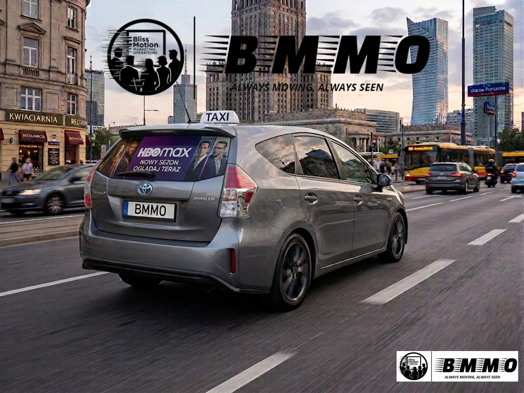 A silver Toyota Prius taxi driving on a busy city street with tall buildings and traffic in the background. The taxi has an HBO Max ad on the rear window and a license plate reading BMMO. There are other vehicles and pedestrians visible on the sidewa