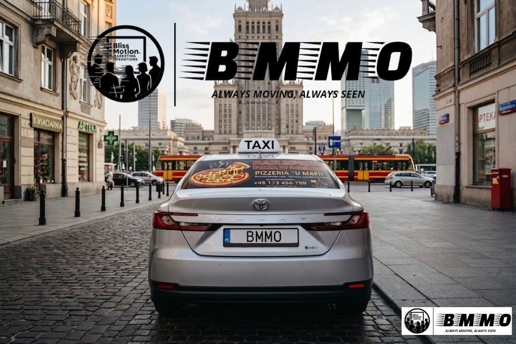 A silver Toyota Camry taxi with a license plate reading 'BMMO' parked on a cobblestone street in a city with tall buildings. The rear window has a pizza advertisement, and the city background shows a tram and other vehicles. There are logos and text 