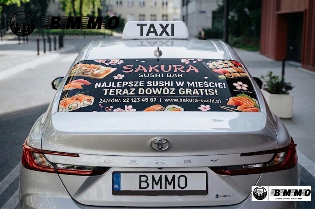 A silver Toyota Camry taxi with a large advertisement on the trunk promoting Sakura Sushi Bar, with images of sushi, cherry blossoms, and text in Polish about delivery and contact details.
