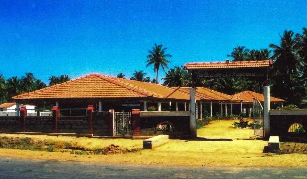 A building with a red-tiled roof, surrounded by palm trees under a clear blue sky.