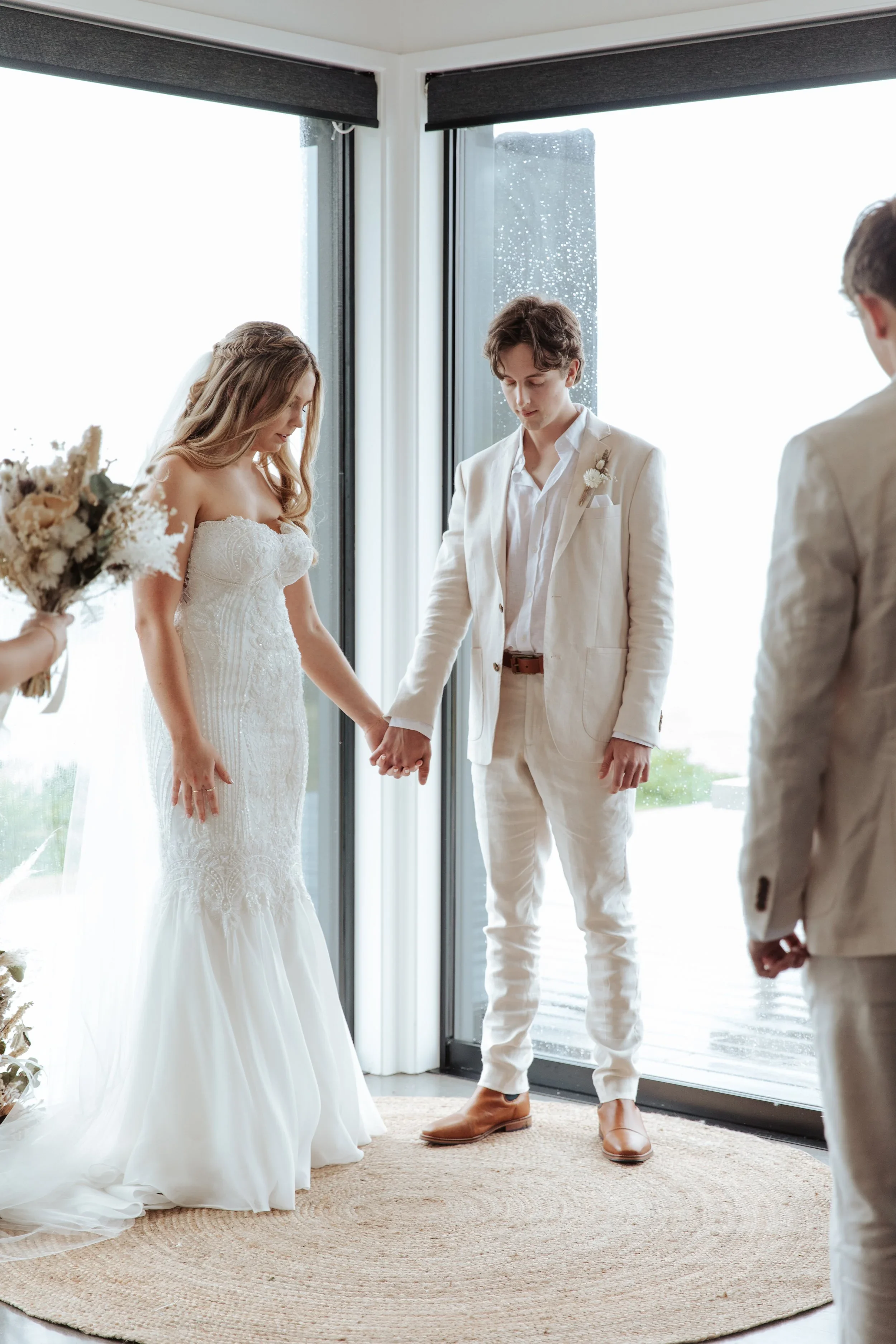 A couple dressed in white wedding attire holding hands during their wedding ceremony.
