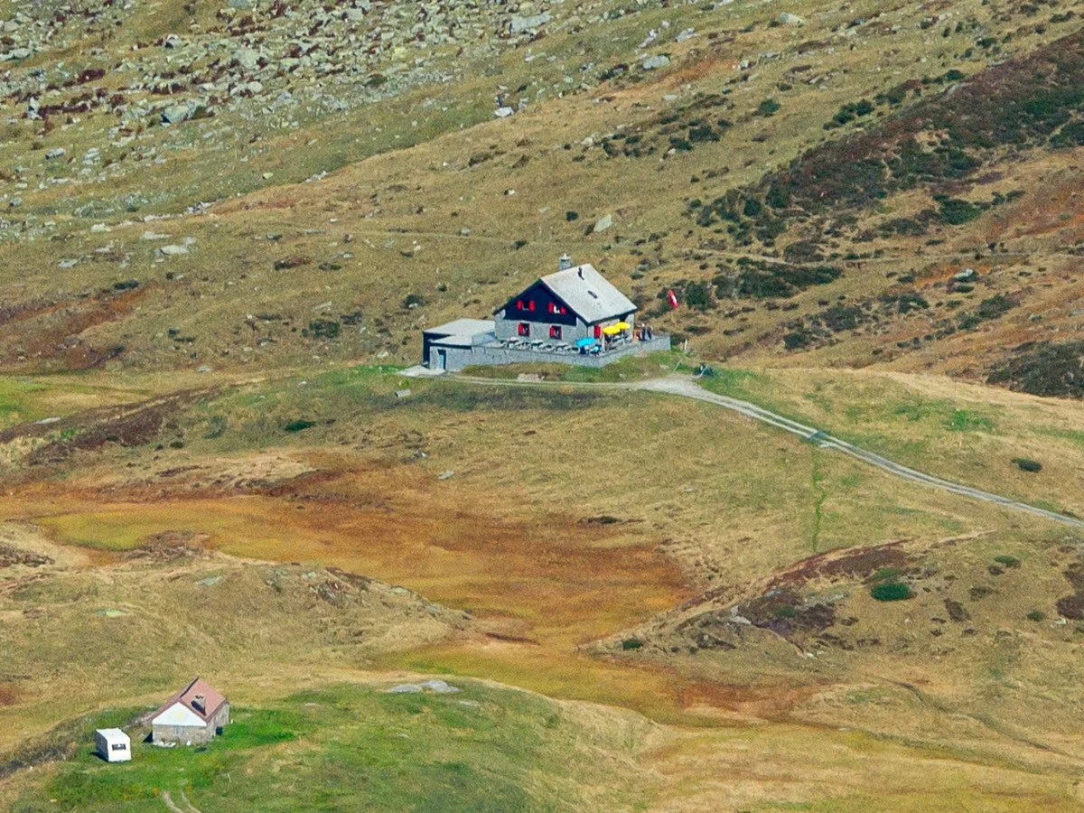 Casa di montagna in una valle aperta con colline e poca vegetazione, piccole case ecupole di colore rosso.
