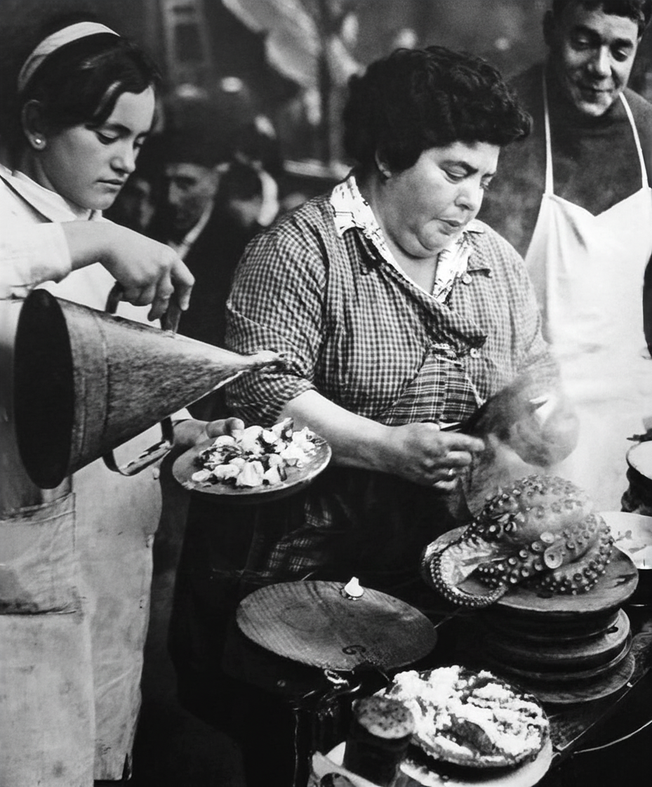 Tres personas en una cocina o puesto de comida preparan y sirven platos y dulces