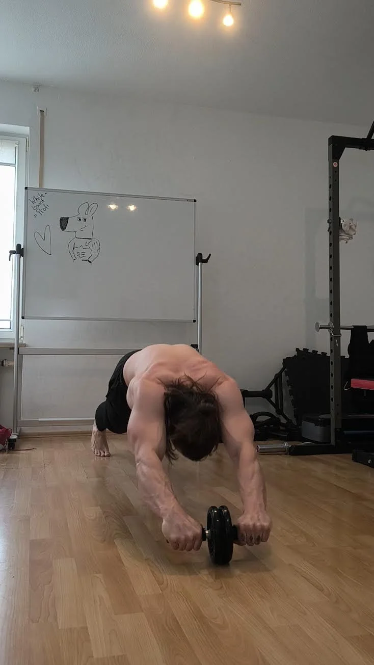 Ein Mann macht eine Plank-Übung mit einem Gewicht auf dem Boden in einem Fitnessraum.