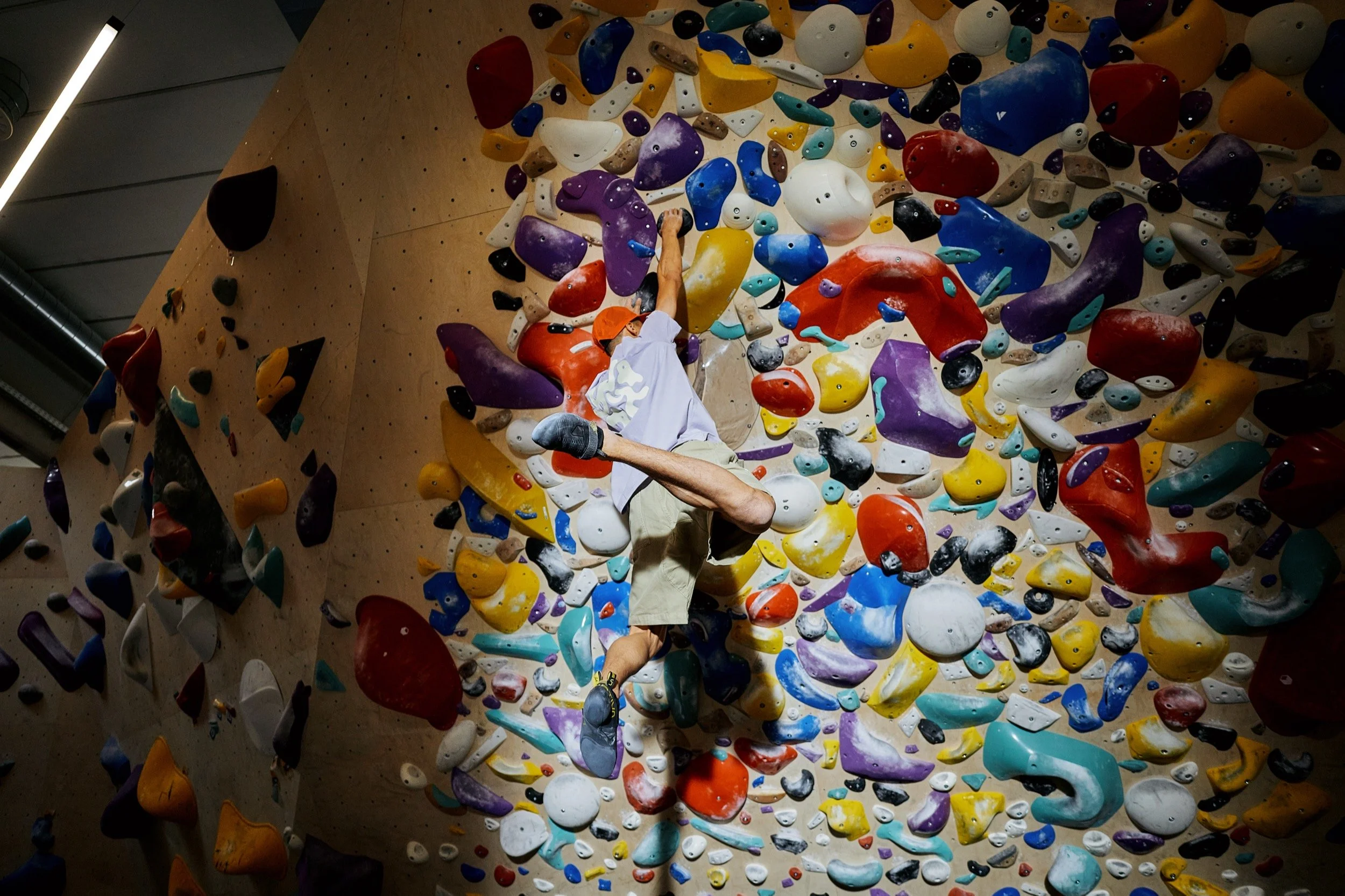 Junge beim Klettern an einer bunten Kletterwand, die mit verschiedenen Tritt- und Griffmarkierungen ausgestattet ist.