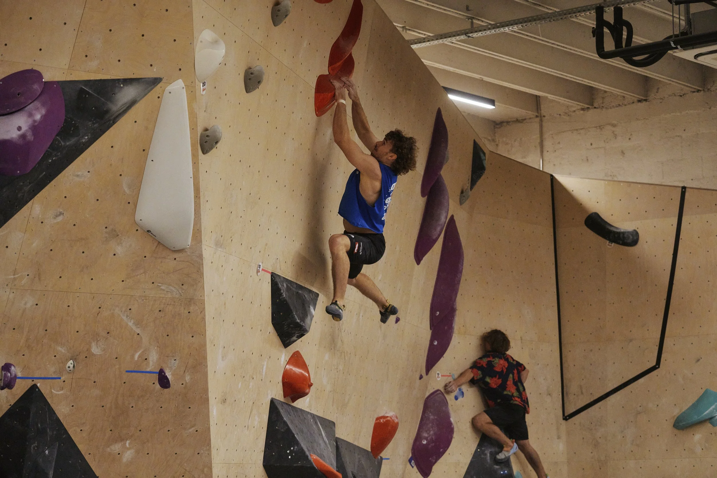 Männliche Kletterer beim Bouldern in einer Kletterhalle.