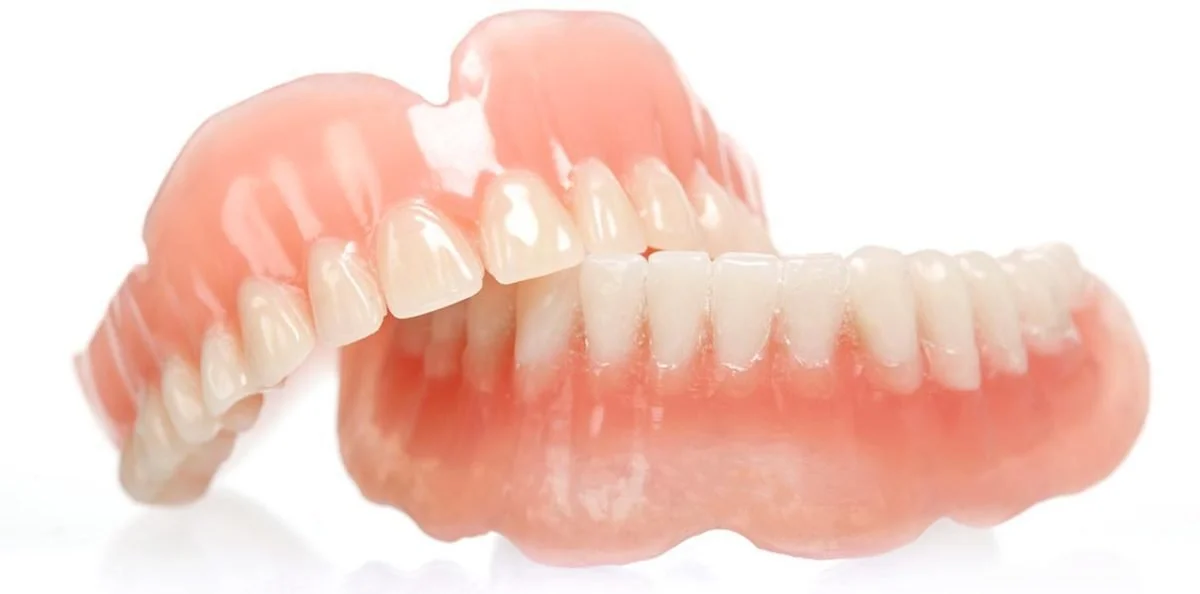 Close-up of a set of dentures with upper and lower teeth against a white background.