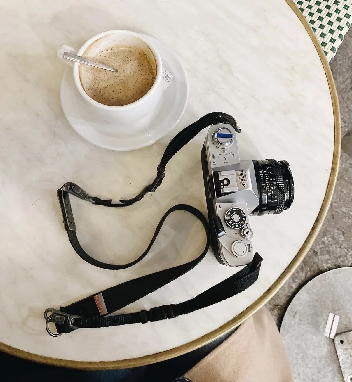 Una càmera i una tassa de cafè sobre una taula rodona.